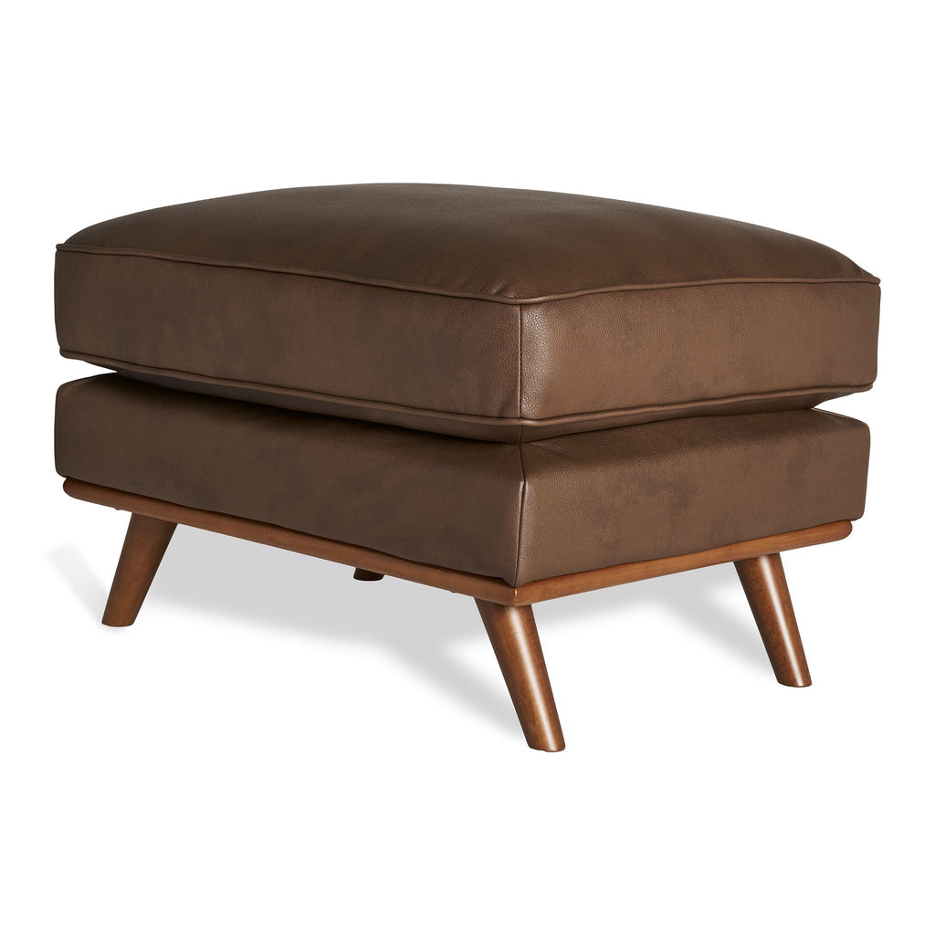The Maddox Ottoman boasts a sleek brown leather finish, rectangular cushion top, and four tapered wooden legs. Its modern design complements both mid-century and contemporary interiors, fitting seamlessly into any living space.