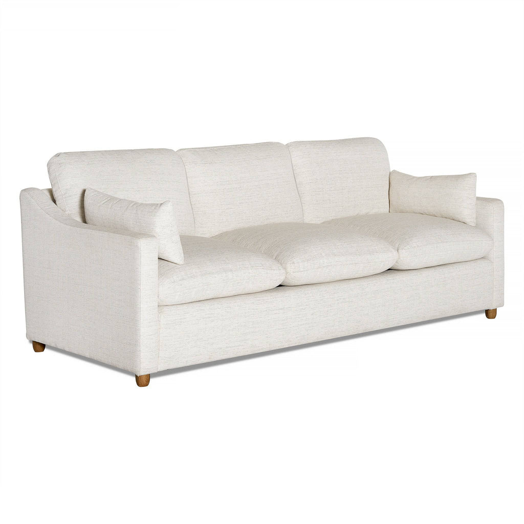The My Cloud Slope Sofa is a three-seater with light beige fabric, plush cushions, matching throw pillows, curved armrests, and wooden legs. Its machine-washable covers add practicality to its style.