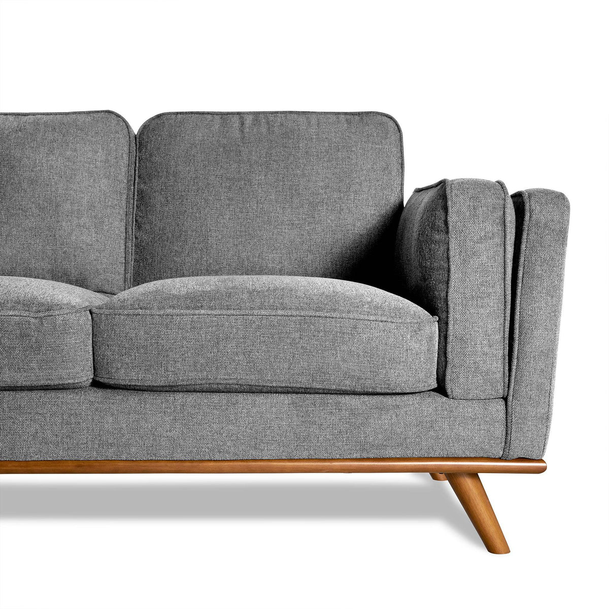 The Maddox is a modern gray fabric sofa with a wooden base and angled legs. It features plush cushions and an armrest, embodying mid-century modern design against a white background, perfect for any living room.