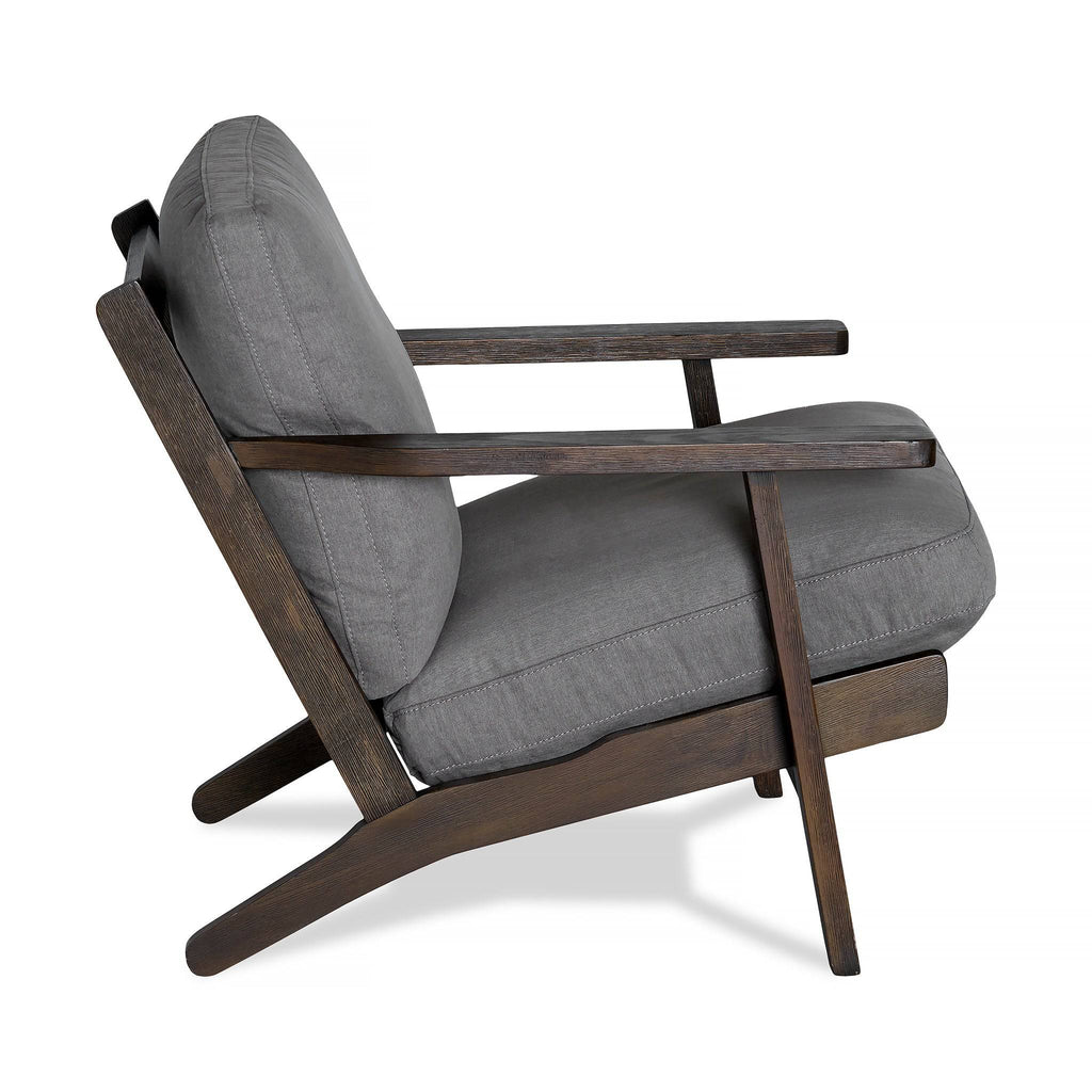 Side view of the Peyton Chair, featuring a stylish dark wooden frame and gray cushions. Its comfortable design includes an angled backrest and minimalist aesthetic, blending mid-century and contemporary styles seamlessly.