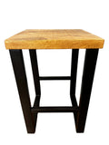The Mango Stool is a small, square accent piece crafted from sustainable mango wood with black metal legs. Its minimalist design features a simple crossbar for support, and the natural wood finish beautifully complements its sleek modern aesthetic.